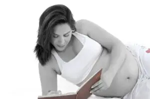 a pregnant woman writing in a notebook
